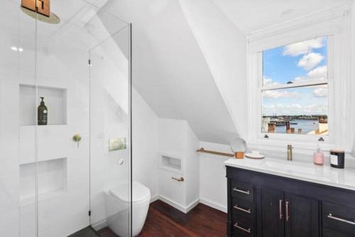 a white bathroom with a toilet and a window at Chic Large 4 Bedroom Barangaroo The Rocks Sydney in Sydney