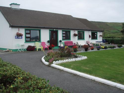 a white house with pink chairs and a yard at Beach View Bed & Breakfast in Allihies