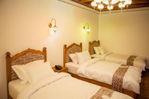 a hotel room with three beds and a chandelier at Istat Boutique Hotel in Bukhara