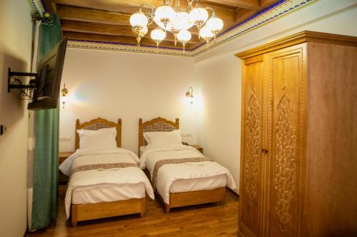 a bedroom with two beds and a chandelier at Istat Boutique Hotel in Bukhara