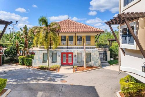a house with a red door and palm trees at 4BR Disney Family Townhouse Resort in Orlando - with Resort Pool, Gym, Games, & Jacuzzi in Orlando