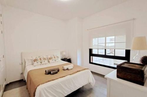 a white bedroom with a bed and a window at Acacias Home Arrecife in Arrecife