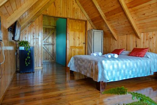 1 dormitorio con 1 cama en una cabaña de madera en Cabaña Indira, en Monteverde