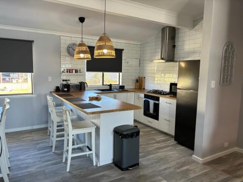 a kitchen with a counter and a island with chairs at Kalbarri Sunset Villa in Kalbarri