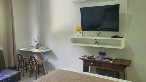 um quarto com uma televisão, uma mesa e uma cama em HOTEL CAVALINHO BRANCO em Águas de Lindoia