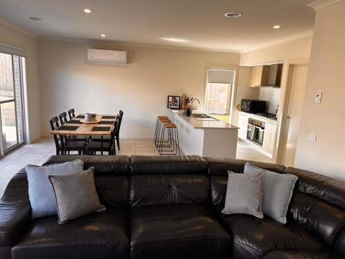 a living room with a black leather couch and a table at Coastal Oasis - 10 mins to Torquay, 10 mins to Geelong ! in Mount Duneed