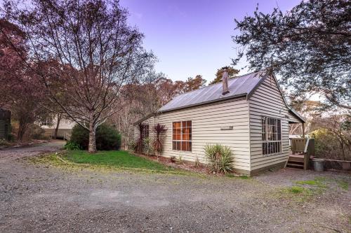 a small white house sitting on the side of a driveway at The Cottages at Hepburn Springs in Hepburn Springs