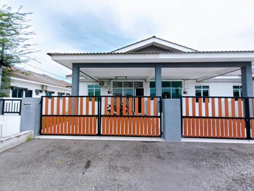 a house with an orange gate in front of it at Manjung Point Homestay in Seri Manjung