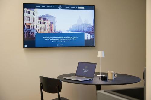 a laptop on a table with a tv on a wall at Palazzina RIVA in Venice