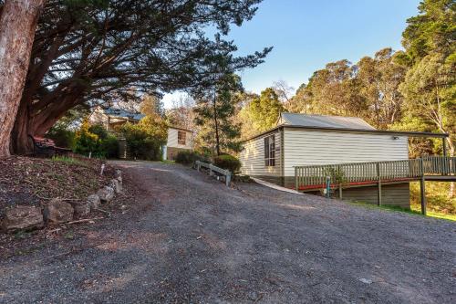 a house with a tree next to a driveway at The Cottages at Hepburn Springs in Hepburn Springs