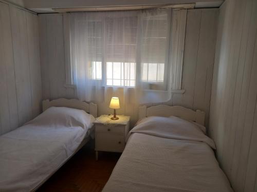2 Betten in einem Zimmer mit Fenster und Lampe in der Unterkunft Marina in Mar del Plata