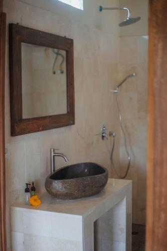 a bathroom with a stone sink and a shower at Nirwa 1 Ubud Guesthouse in Ubud