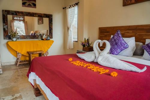 a bedroom with two swans and flowers on a bed at Nirwa 1 Ubud Guesthouse in Ubud