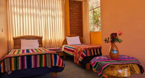 una habitación con 2 camas y un jarrón con flores en Amantani Samary Lodge en Ocosuyo