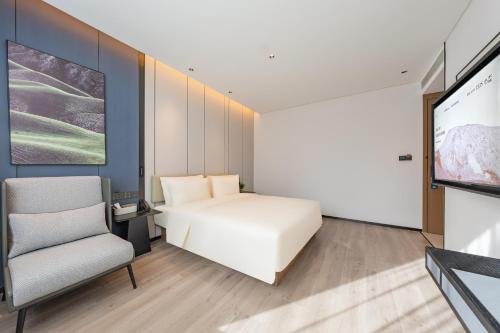 a bedroom with a bed and a chair and a tv at Atour Hotel Guangzhou Pazhou Exhibition Center Information Port-Free shuttle bus to Canton Fair in Guangzhou