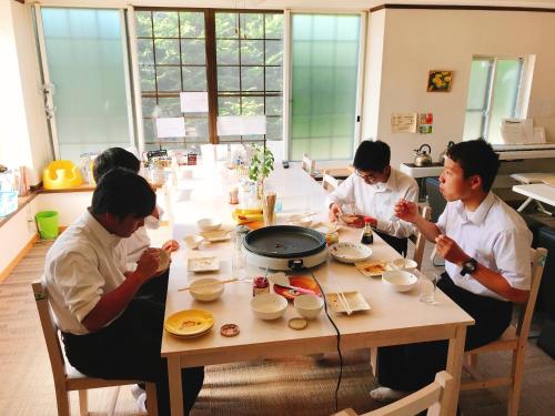 平川市にあるMisato Memorial Hall - Vacation STAY 61405vの食卓に座って食べ物を食べる男たち