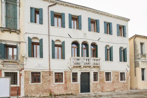 an old white building with green shuttered windows at Palazzina RIVA in Venice