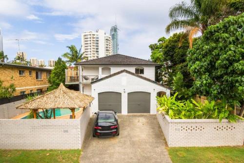 a car parked in front of a white house at Paradise Villas- Villa 1 in Gold Coast