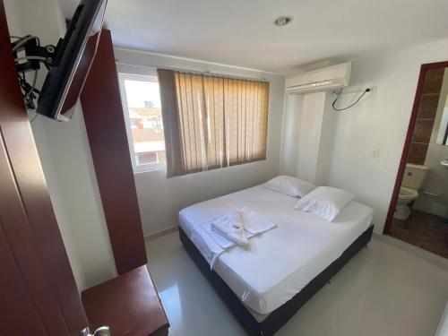 1 dormitorio con 1 cama blanca y ventana en HOTEL SAN ÁNGEL VILLAVICENCIO, en Villavicencio