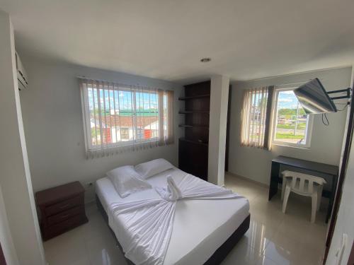 1 dormitorio con 1 cama blanca y 2 ventanas en HOTEL SAN ÁNGEL VILLAVICENCIO, en Villavicencio