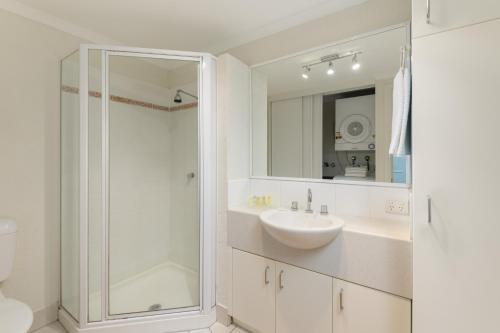a white bathroom with a sink and a shower at Coral Apartments Port Douglas in Port Douglas