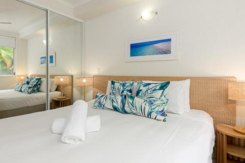 um quarto com uma cama grande e almofadas azuis e brancas em Coral Apartments Port Douglas em Port Douglas