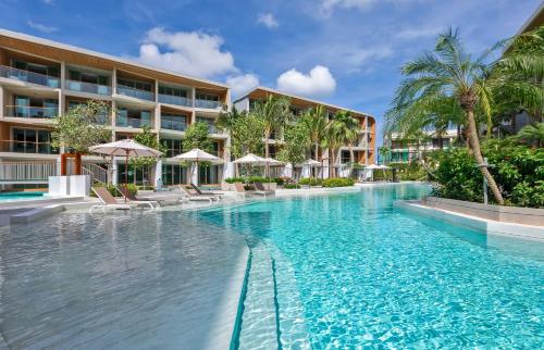 a swimming pool in front of a hotel at Wyndham Grand Nai Harn Beach Phuket in Nai Harn Beach