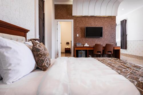a bedroom with a large white bed with a desk at Mekong Gia Lai Hotel - Me Kong Pleiku in Pleiku