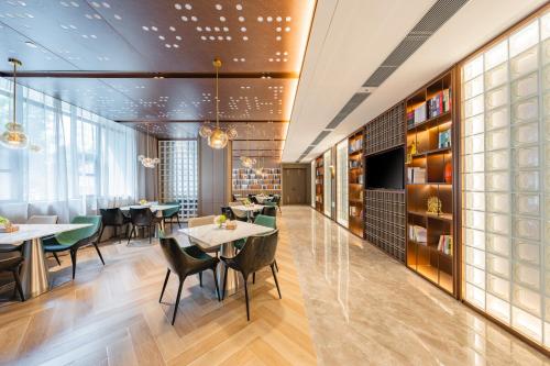 a restaurant with tables and chairs and a large window at Atour Hotel Guangzhou Pazhou Exhibition Center Information Port-Free shuttle bus to Canton Fair in Guangzhou