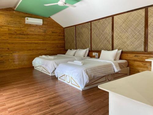Nov Koh Kong Resort في Phumĭ Srê Thmei: سريرين في غرفة بجدران خشبية