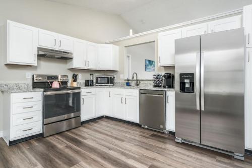una cocina con armarios blancos y electrodomésticos de acero inoxidable en Peaceful Modern Home near Avon, en Avon
