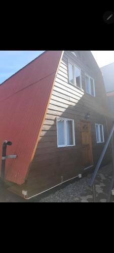 a large wooden house with a red roof at Cabaña Fortunata in Puerto Williams