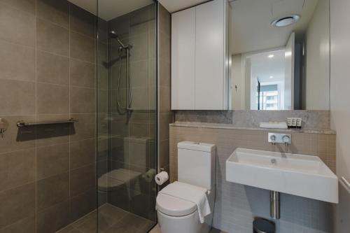 a bathroom with a toilet and a sink and a shower at City Center High-Rise Apartment with Parking in Canberra