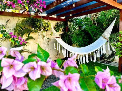 a hammock in a garden with pink flowers at Airport Traveler's home. in Alajuela City