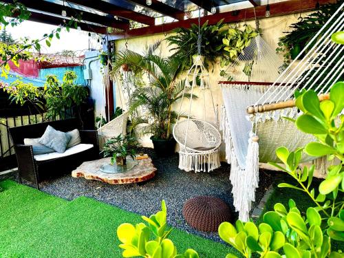 eine Terrasse mit Hängematte, Stühlen und Pflanzen in der Unterkunft Airport Traveler's home. in Alajuela