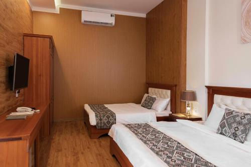 a hotel room with two beds and a television at Mekong Gia Lai Hotel - Me Kong Pleiku in Pleiku