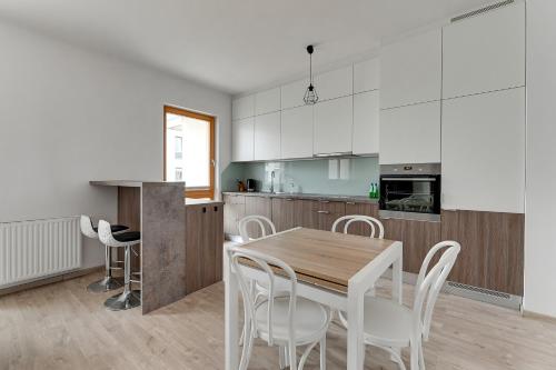cocina con mesa de madera y sillas blancas en Mila Baltica by Grand Apartments, en Gdansk