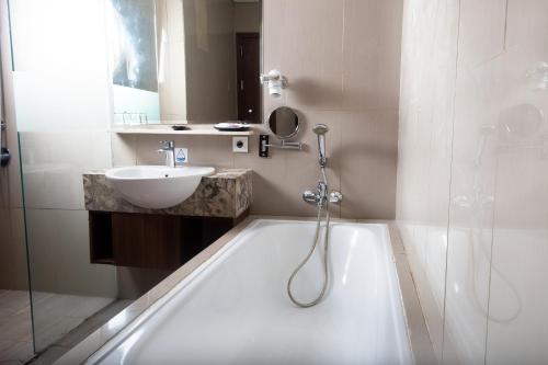 a bathroom with a tub and a sink and a shower at Pakons Prime Hotel in Tangerang