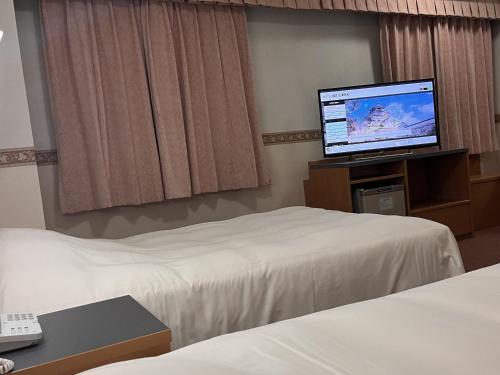 a hotel room with two beds and a flat screen tv at Hotel Alpha-One Aizuwakamatsu in Aizuwakamatsu