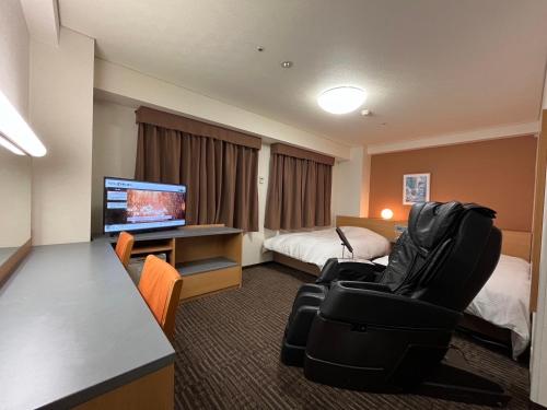 ein Hotelzimmer mit einem Bett, einem Schreibtisch und Stühlen in der Unterkunft Hotel Alpha-One Koriyama Higashiguchi in Koriyama