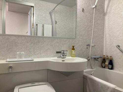 ein Badezimmer mit einem Waschbecken, einem WC und einem Spiegel in der Unterkunft Hotel Alpha-One Koriyama in Koriyama