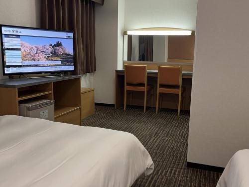 Cette chambre comprend un lit et un bureau avec une télévision. dans l'établissement Hotel Alpha-One Koriyama, à Koriyama