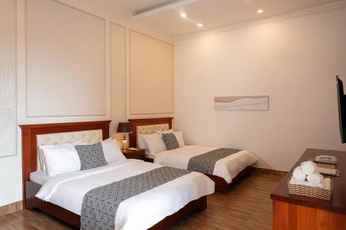 a hotel room with two beds and a television at Mekong Gia Lai Hotel - Me Kong Pleiku in Pleiku