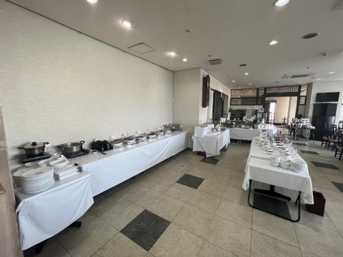 鶴岡市にあるホテルアルファーワン鶴岡のダイニングルーム(白いテーブル、白い料理付)