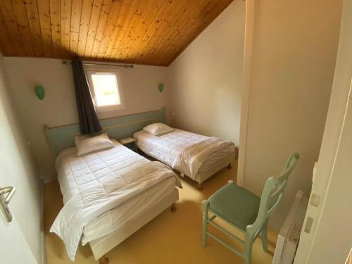 - 2 lits dans une chambre avec une chaise et une fenêtre dans l'établissement Maison 2 chambres avec terrasse et parking près forêt, plage et pistes cyclables à Saint-Jean-de-Monts - FR-1-323-522, à Saint-Jean-de-Monts