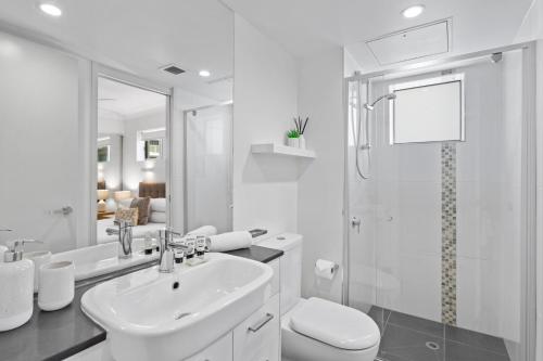 La salle de bains blanche est pourvue d'un lavabo et d'une douche. dans l'établissement Private 2-Bed Apartment & 5 minutes walk to QPAC, à Brisbane