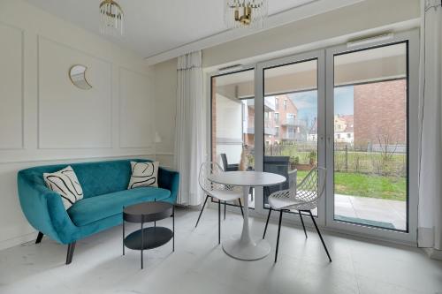sala de estar con sofá azul, mesa y sillas en Sunny Garden by Grand Apartments en Gdansk