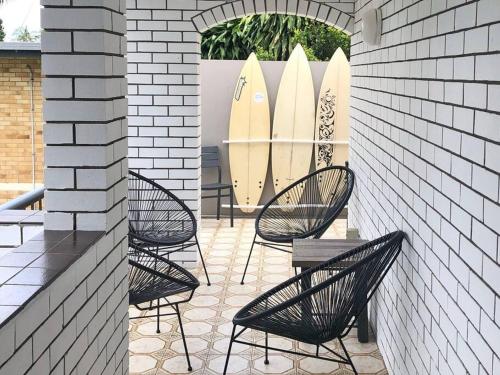 a patio with chairs and surfboards in a building at Paradise Villas - Villa 2 in Gold Coast