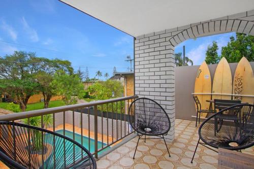 a balcony with two chairs and a table and surfboards at Paradise Villas - Villa 2 in Gold Coast