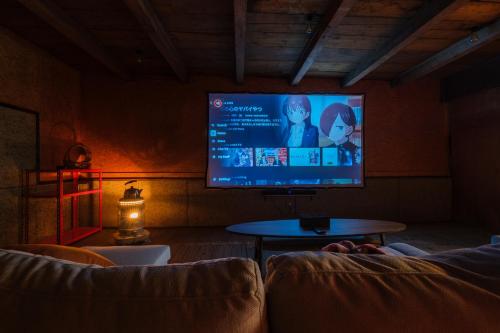 sala de estar con TV, sofá y mesa en Stone Lodge 小樽, en Kita-hamachō